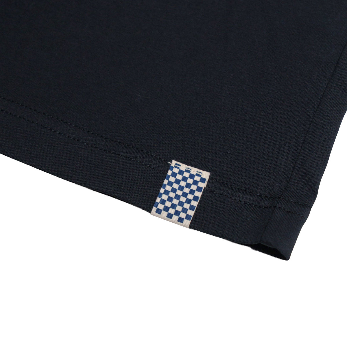 Close-up of Road Trip Black Tee showing Blue and white checkerboard woven label sewn into side seam - Slowride Supply