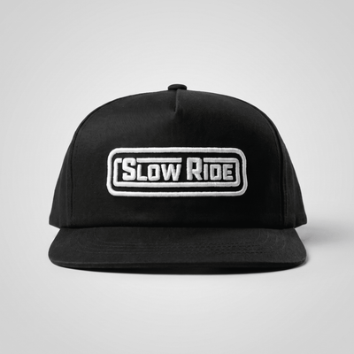 Radio Unstructured Snapback front view, Black with white embroidered "Slow Ride" text in rounded rectangular patch, Black